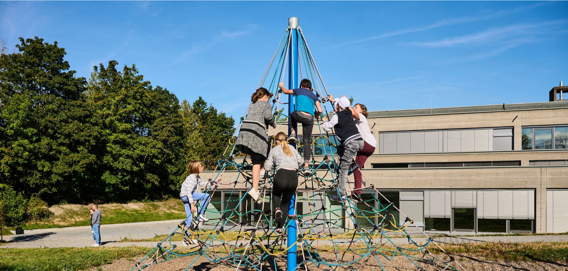 Schülerinnen und Schüler klettern auf dem Schulhof.